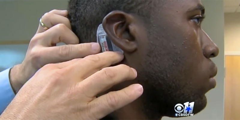 A researcher attaches a device behind a patient's ear