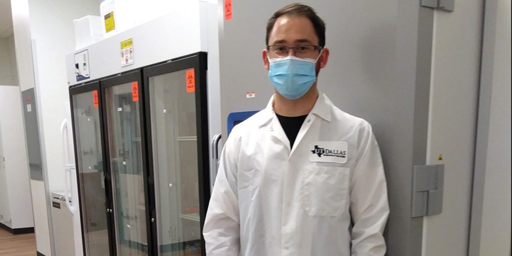 Luke Joyce, a research associate in biological sciences, stands next to one of UT Dallas’ new freezers that was lent to the city of Grand Prairie to store COVID-19 vaccines.
