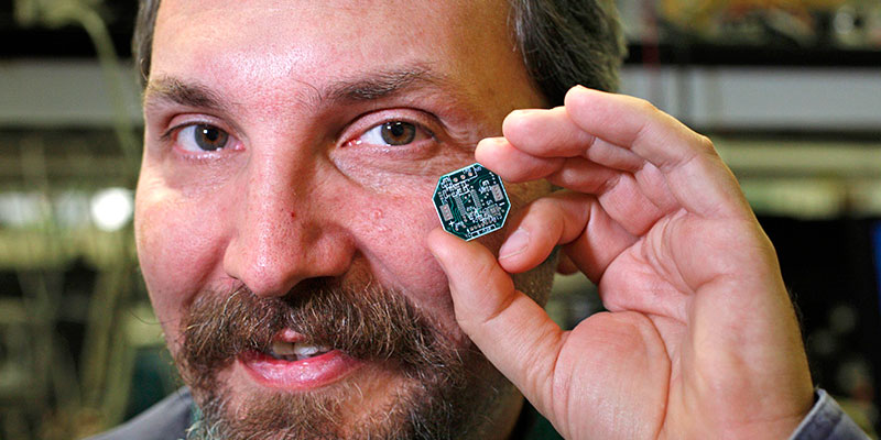 A person holds a microchip near his eye. 